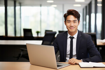 オフィスでスーツを着てノートパソコンを使って仕事をしている男性のビジネスマン・会社員