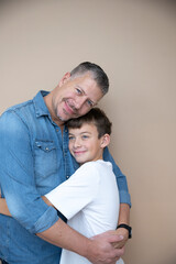 Fototapeta premium father and son are posing in front of brown background, love, family, teenager