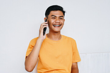 Cheerful Asian teenage student with dental braces talking on the phone with happy expression