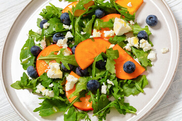 arugula persimmon cheese berries salad, top view