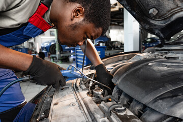 Young African male mechanic repairs car in garage close up
