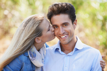 Happy couple, portrait and kiss on cheek in nature for love, bonding or support in relax for...