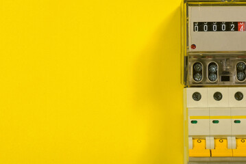 Electricity meter and automatic switch circuit breaker on the yellow flat lay background with copy...