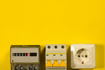 Electricity meter and automatic switch circuit breaker on the yellow flat lay background with copy space.