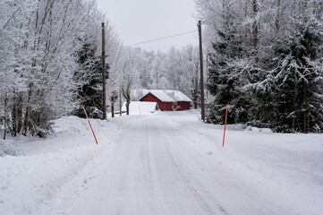 White snowy road with red farm building beside