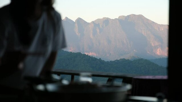 Blurred of a woman cooking and eating Moo Kata, Thai barbecue grill pork with beautiful mountain views