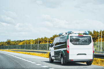 A police van with a mobile radar camera monitors the speed of traffic on a highway. A warning sign...