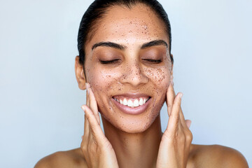 Facial granule scrub and massage. Skin care beauty portrait. Young happy woman is applying peeling...