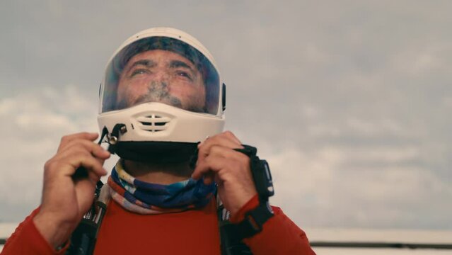 A bearded skydiver putting his helmet on