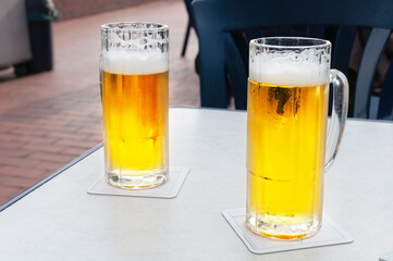 Glasses of cold beer on white table