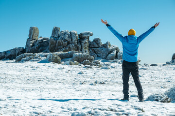 Man enjoying hiking in the snow and celebrating reaching the top
