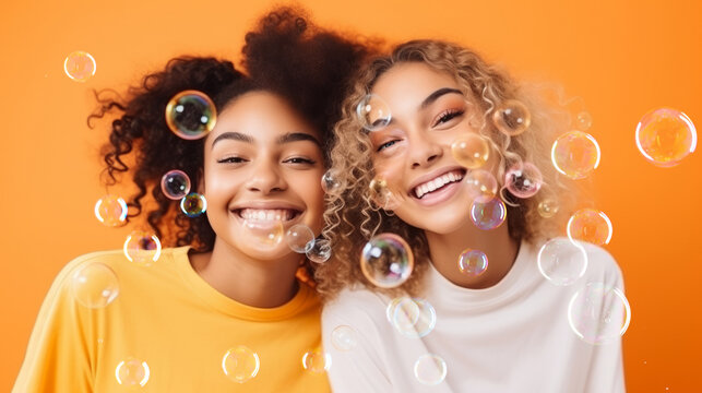 Cheerful and trendy multiethnic teenage girls in front of orange background