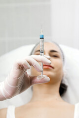 A female cosmetologist in gloves is preparing to give a young woman a cosmetological procedure. Modern dermatology clinic, cosmetic procedures and cosmetic surgery