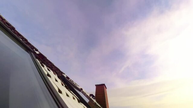 Dachfenster in verschneitem Dach mit sich spiegelnden Wolken die Abends im Zeitraffer vorbeiziehen, rote Ziegel, Dachd&auml;mmung