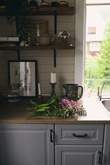 rustic dark wooden cottage kitchen in grey and brown colors with candles and summer garden flowers bouquet. Simple quite life.