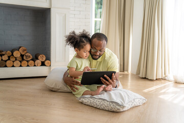 Portrait of African American father and daughter using laptop watching video, smiling while sitting...