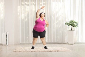 Corpulent woman stretching arms and exercising at home