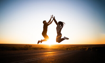 Husband and wife jumping. It is sunset. They are happy, they are in love