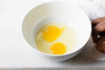 Organic raw eggs in a white mixing bowl for baking and cooking