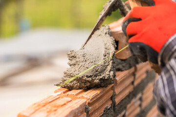 Hand worker masonry brickwork trowel construction site wall concrete background - 720051047