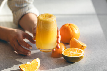 Freshly squeezed orange juice in female hands, close up.