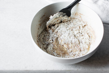Folding flour into batter with a silicone spatula, mixing flour into batter, process of making cake or Madeleines