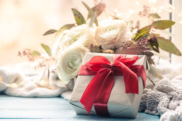 Festive background with gift box and flowers.
