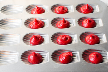 Red velvet madeleine batter pipped into a madeleine pan, process of making madeleines, making...