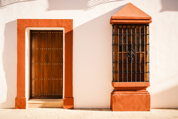 Detail of an old house in Ronda, Spain with traditional wooden door and grated window.