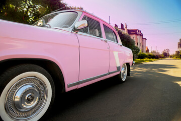 retro car near a private house on the road. Sunset. Bright car. Round headlights. High quality photo