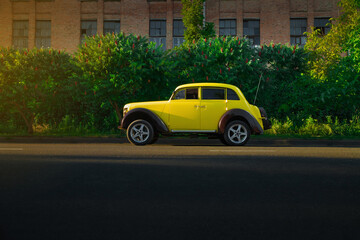 retro car near a private house on the road. Sunset. Bright car. Round headlights. High quality photo