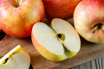 Naklejka na ściany i meble Fresh harvesting sliced red apples on wooden board. Half apple closeup.