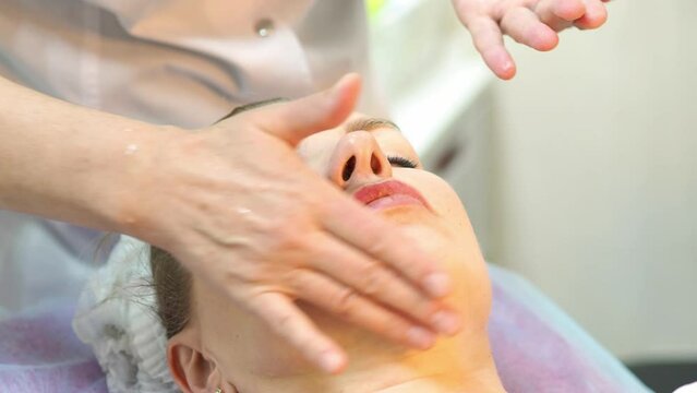 person receiving a massage. A cosmetologist gives a massage to a middle-aged woman. Women's beauty and health. Beauty procedures concept. A woman's face undergoing a cosmetic procedure. Hands of a cos