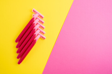 Pink women's razors isolated on yellow and pink background. Pink women's disposable razors. Skin and body care concept. Depilation. Place for text