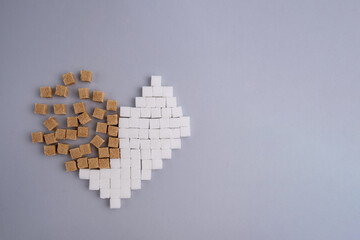 Cubes of refined sugar on a gray background. Broken heart made from white and brown sugar cubes. A...