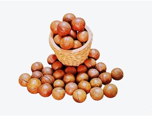 Here are some macadamia nuts in a brown wicker basket, and some on the ground nearby. Macadamia nuts have brown skins, white insides, and are cooked by roasting. If they are ripe, It will be white, 