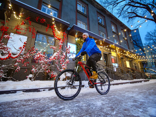A man rides a bicycle along a beautifully decorated street in a winter city