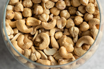 Mix of cashews and hazelnuts in a glass vase, close-up.