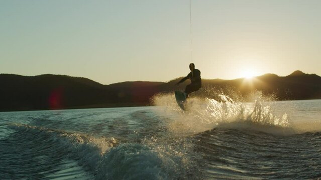 An elderly person wake boarding on a lake at sunset
