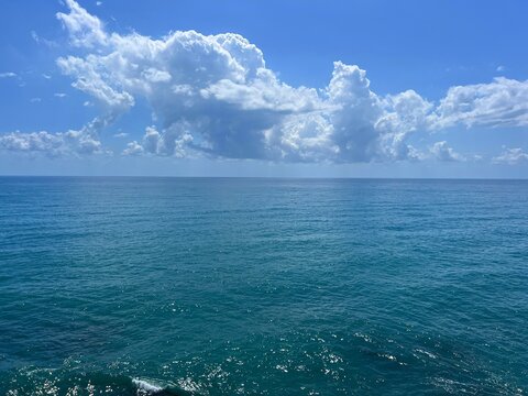 Blue sea shiny water and beatiful sky clouds on the horizon.
