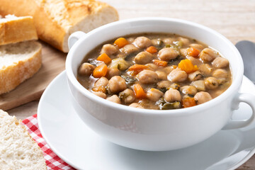Chickpeas soup with vegetables in bowl on wooden table