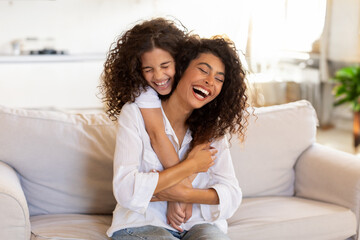 Happy mother and daughter hugging and laughing, girl embracing mom from back, cuddling, enjoying...