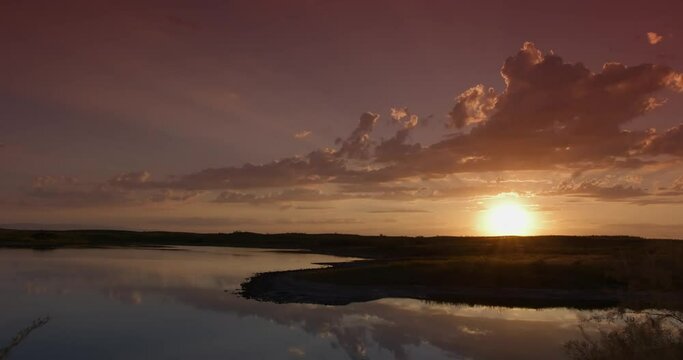 Sunrise on cloudy morning over calm lake in calm weather