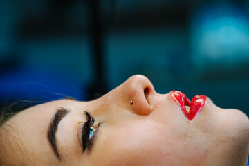 Young woman lies on the couch in the beauty salon and her lips are painted with red lipstick.