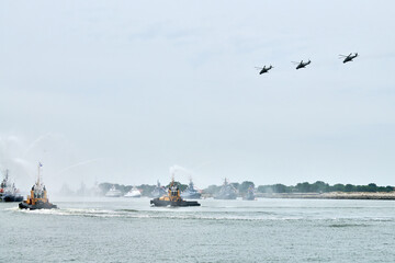 Fireboat sailing along Russian naval forces parade warships with military helicopters along...