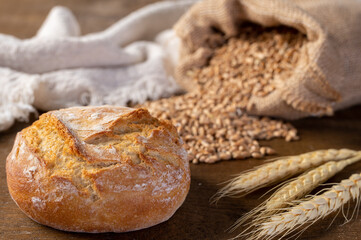 Bakery - Round bread close up. Freshly baked bread with a golden crust on rustic wooden background.