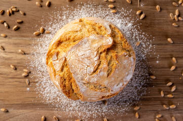 Bakery - Round bread close up. Freshly baked bread with a golden crust on rustic wooden background. Top view.