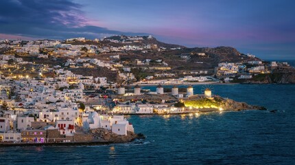 Naklejka na ściany i meble Aerial view of the illuminated old town of Mykonos island until the famous windmills during evening, Cyclades, Greece
