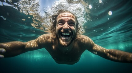 Close-up of a smiling happy man swimming underwater in a pool or sea. Healthy lifestyle, Vacations, travel, Sports and swimming concepts.