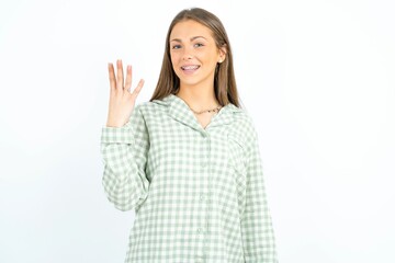 Beautiful young woman wearing green plaid pyjama smiling and looking friendly, showing number four or fourth with hand forward, counting down